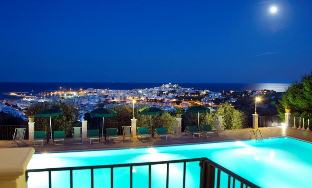 a swimming pool with a view of a city at night at Residence Chiesiola in Vieste