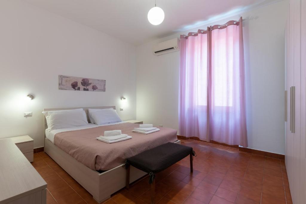 - une chambre avec un lit, une chaise et des rideaux roses dans l'établissement Evelina in Trastevere, à Rome