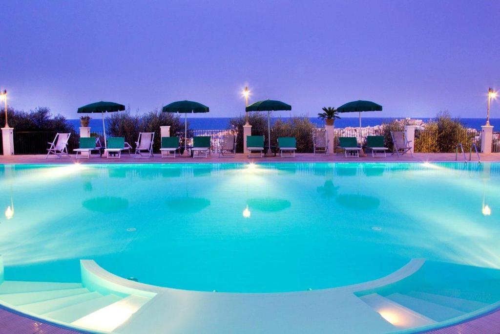 a large swimming pool at night with chairs and umbrellas at Residence Chiesiola in Vieste
