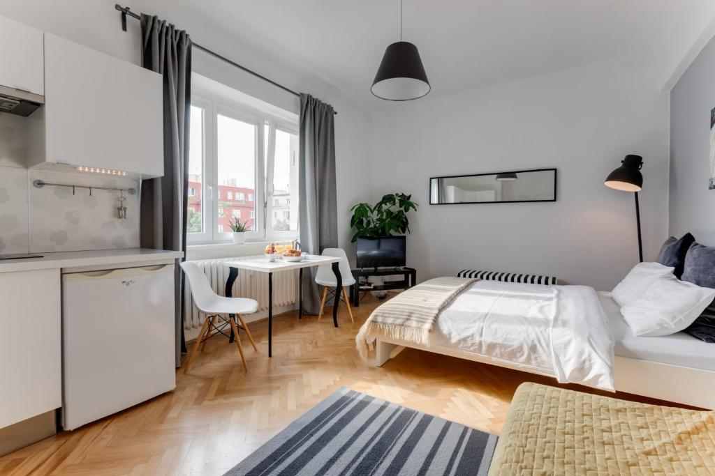 ein weißes Schlafzimmer mit einem Bett und einem Tisch in der Unterkunft JT's Apartments Biskupcova str. in Prag