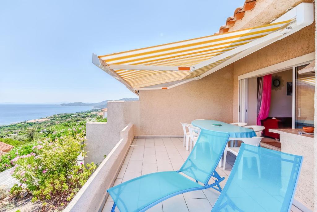 d'un balcon avec des chaises bleues et une vue sur l'océan. dans l'établissement EL ORO - Terrasse Vue Mer et piscine - Porto Vecchio, à Porto-Vecchio