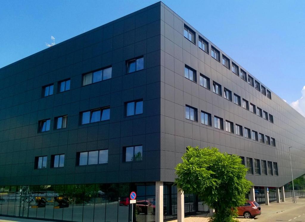 a large gray building with a tree in front of it at Hotel Meeting in Toruń