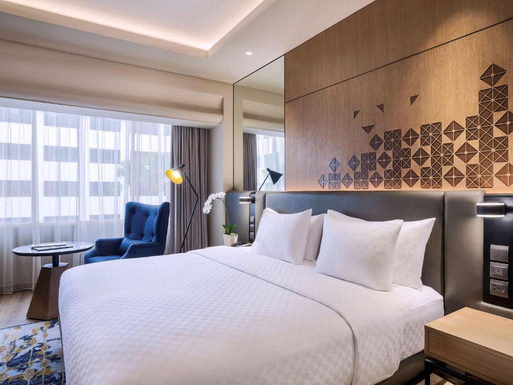 a hotel room with a bed and a blue chair at Mercure Jakarta Batavia in Jakarta