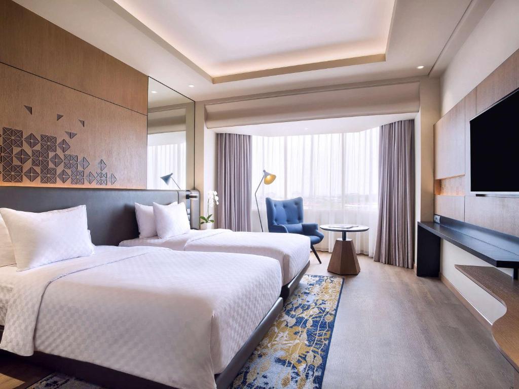 a hotel room with two beds and a television at Mercure Jakarta Batavia in Jakarta