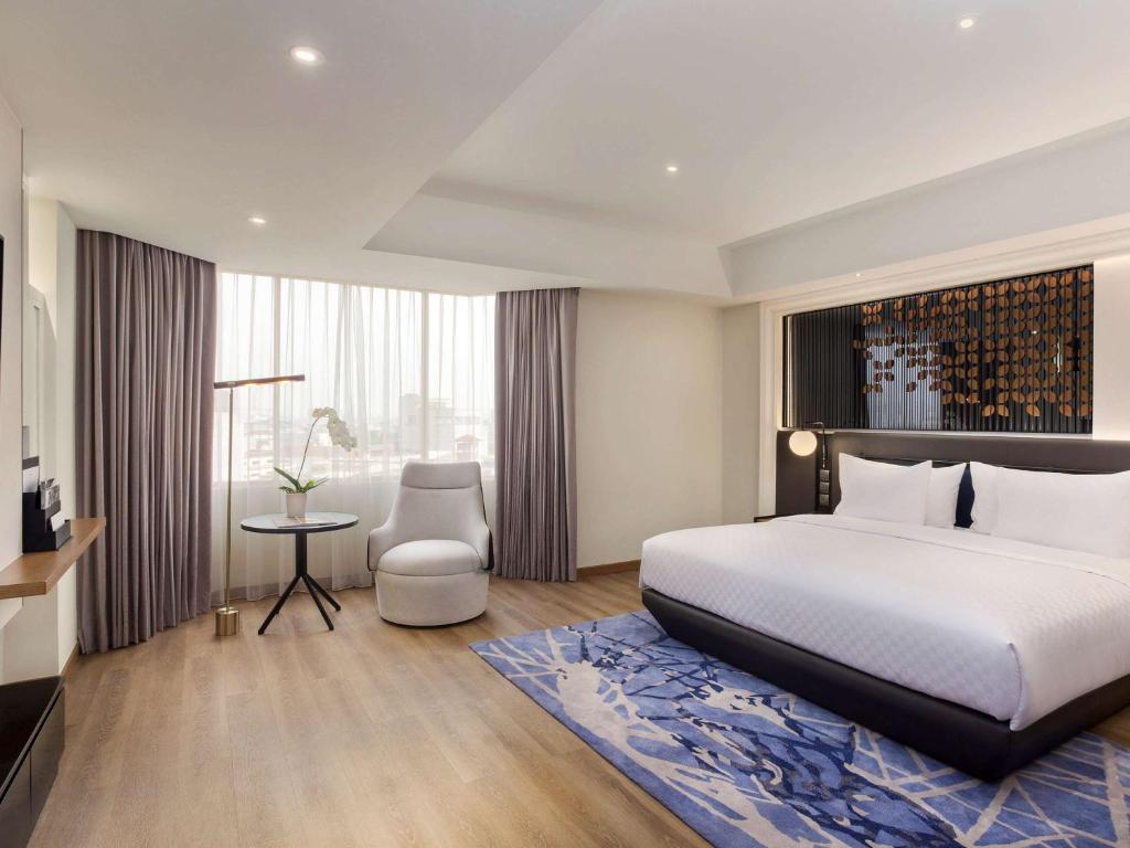 a hotel room with a bed and a table and a chair at Mercure Jakarta Batavia in Jakarta