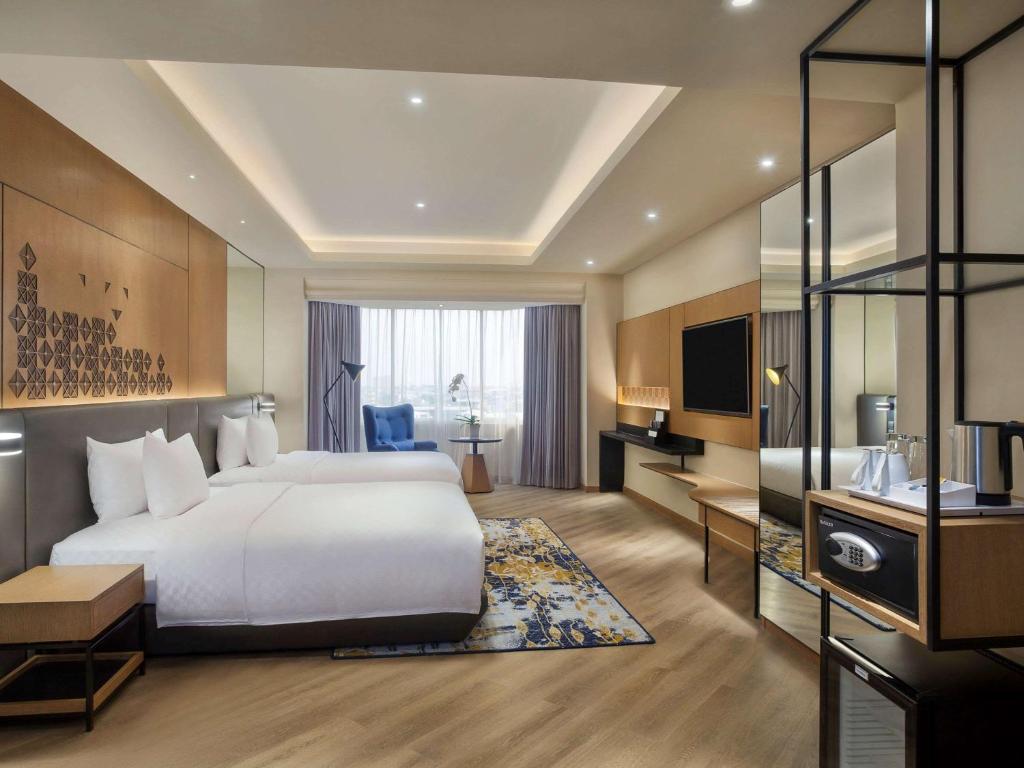 a hotel room with a large bed and a television at Mercure Jakarta Batavia in Jakarta