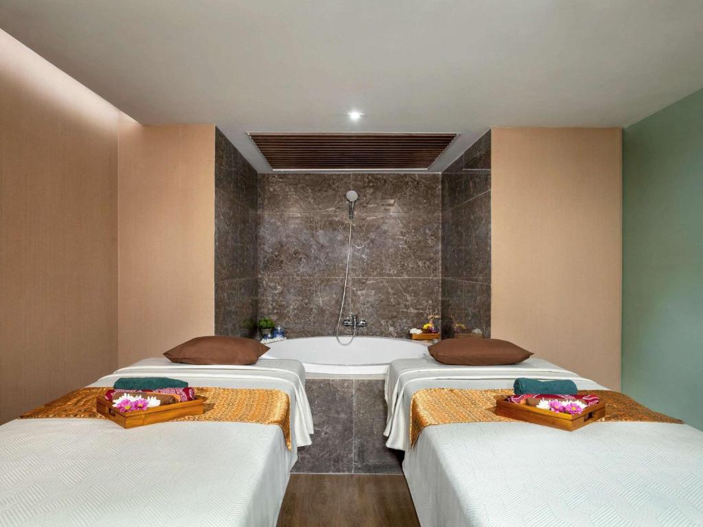 two beds in a room with a bath tub at Mercure Jakarta Batavia in Jakarta