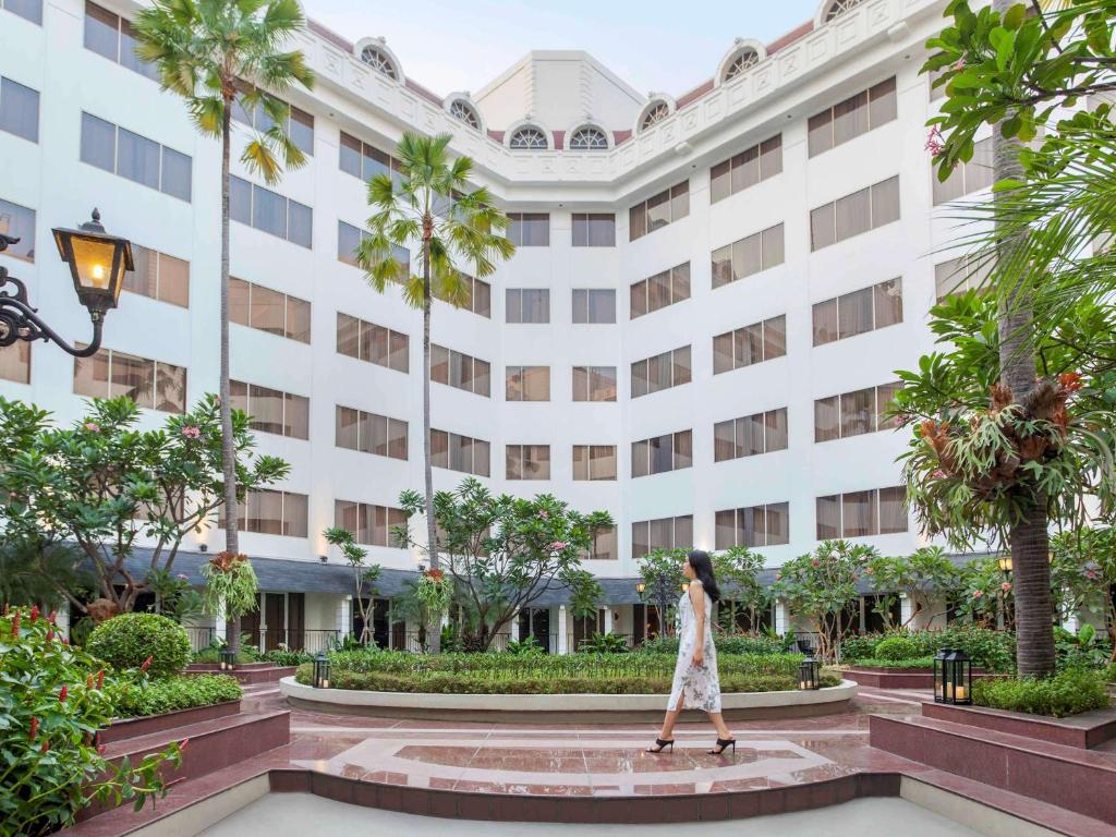 a woman walking in front of a building at Mercure Jakarta Batavia in Jakarta