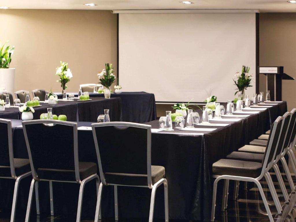 a set of tables and chairs in a room with a screen at Mövenpick Hotel Casablanca in Casablanca