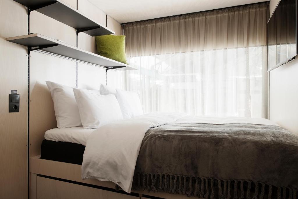 a bedroom with a bed with white pillows and a window at Hektor Container Hotel in Tallinn