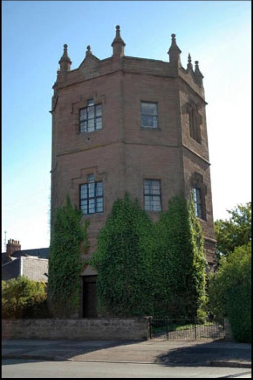 a tall brick building with bushes in front of it at Montrose Watertower in Montrose