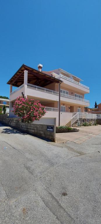 Apartment Ivana with a nice see view في كافتات: مبنى ابيض كبير وامامه زهور