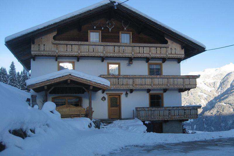 une grande maison en bois avec de la neige devant elle dans l'établissement Ferienhaus Berggrubenhof, à Fügen