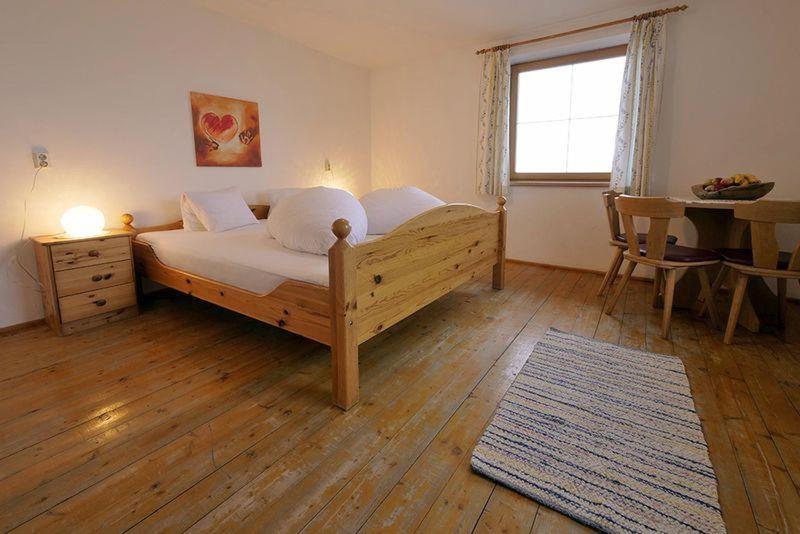 una camera da letto con un letto, un tavolo e una finestra di Ferienhaus Berggrubenhof a Fügen