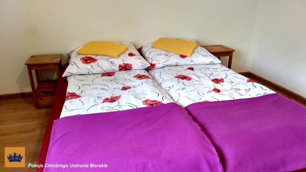 two beds in a room with purple sheets and flowers at Pokoje Chrobrego pokoje gościnne w centrum blisko morza in Ustronie Morskie