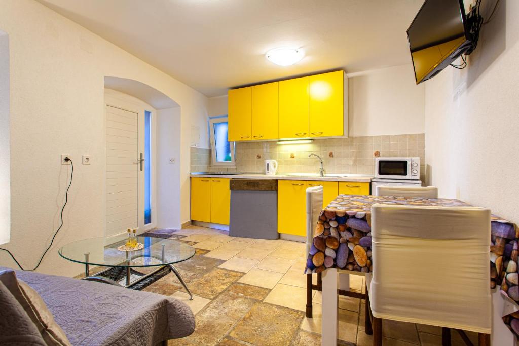 a kitchen with yellow cabinets and a table at Room M in Cres