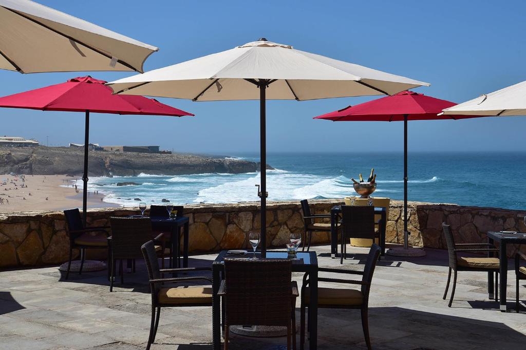 a restaurant with tables and umbrellas on the beach at Hotel Fortaleza do Guincho Relais & Châteaux in Cascais