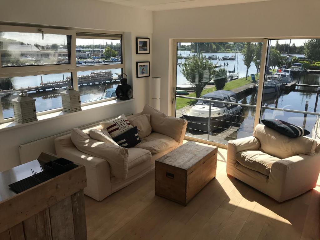 a living room with two couches and a large window at The Boathouse with boat in Aalsmeer