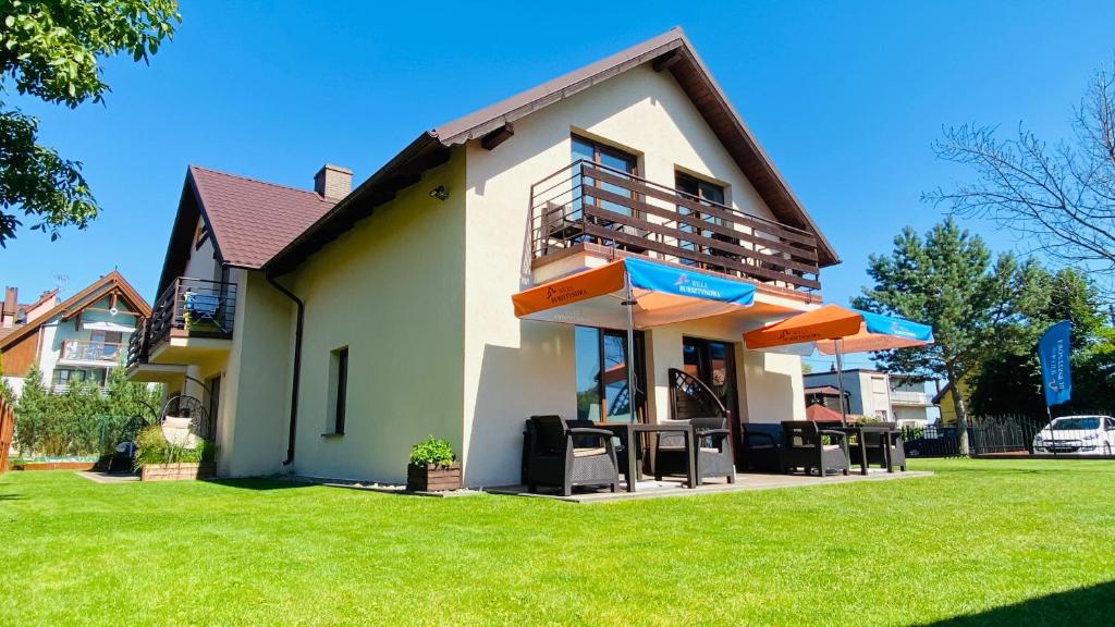 a house with a balcony and a lawn at Willa Bursztynowa in Kąty Rybackie