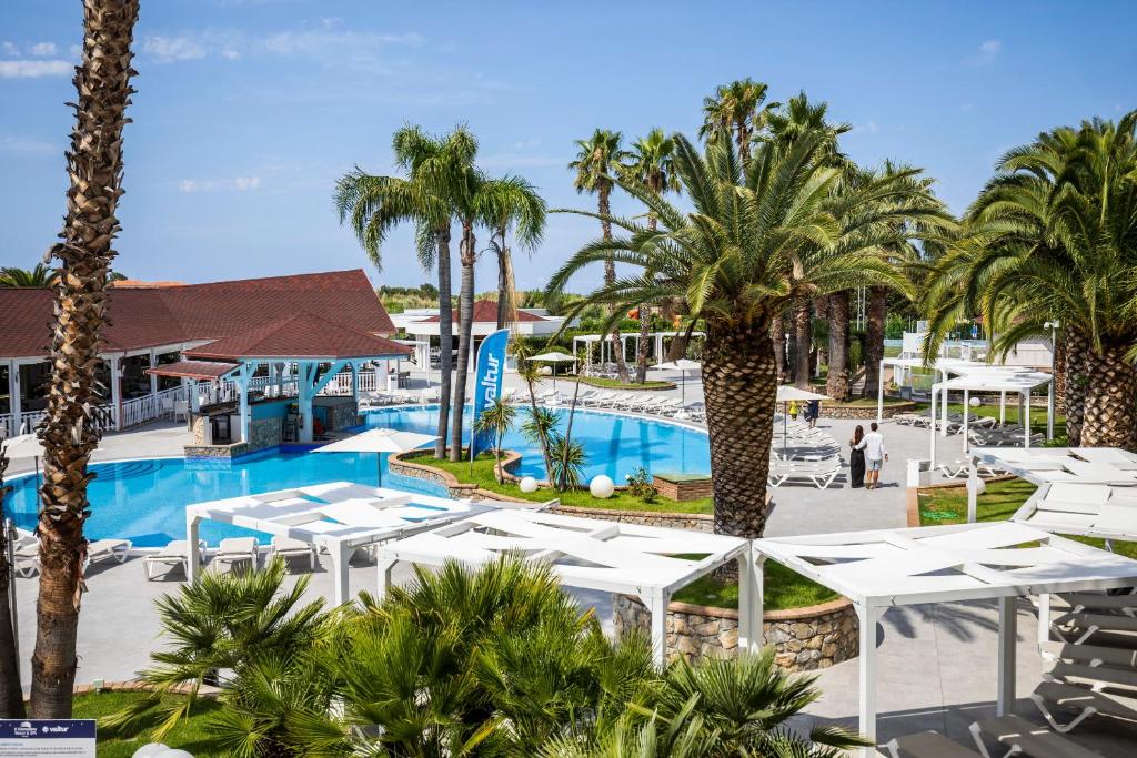 - une vue sur la piscine d'un complexe avec des palmiers dans l'établissement Valtur Il Cormorano Resort & Spa, à Grisolia