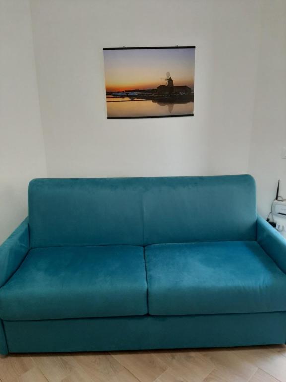 un divano blu in una stanza con una foto sul muro di LA NICCHIA a Marsala
