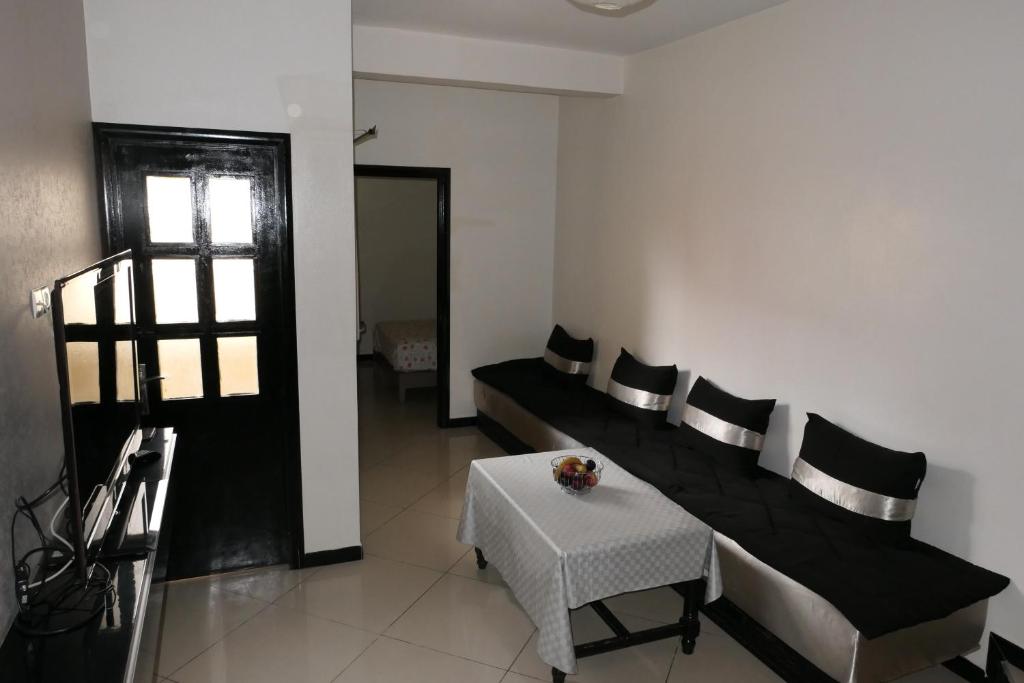 una sala de estar con un banco negro y una mesa en Le Calme a Temara, en Temara