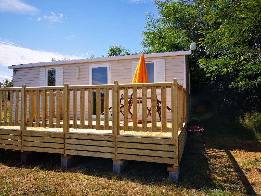 une maison avec un parasol orange sur une terrasse en bois dans l'établissement Nature Monchy, à Campneuseville