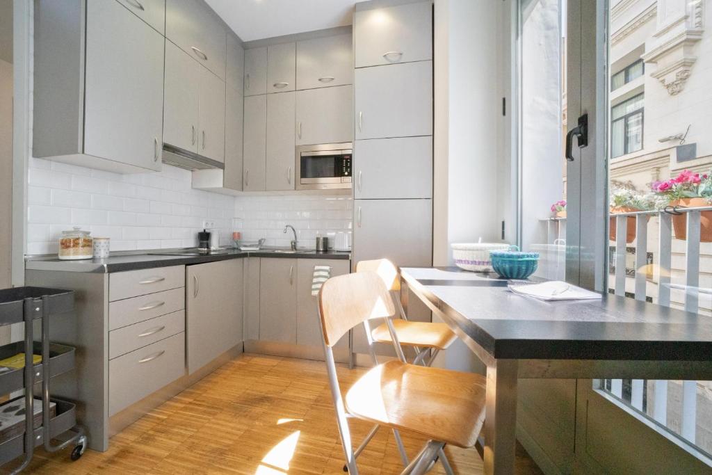 a kitchen with white cabinets and a table and chairs at Apartamentos Moratín Las Letras in Madrid