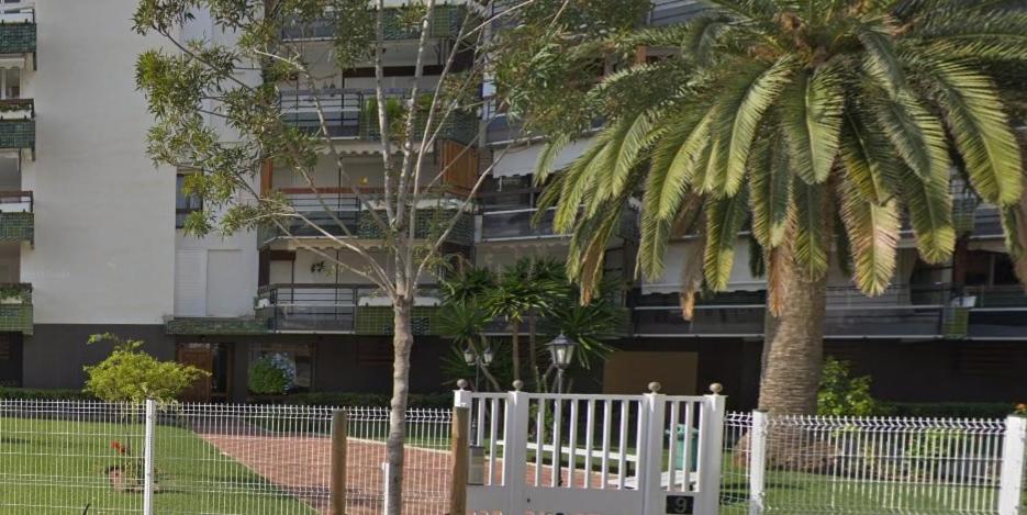 una valla blanca con dos palmeras frente a un edificio en Apartament Formentor - Salou, en Salou