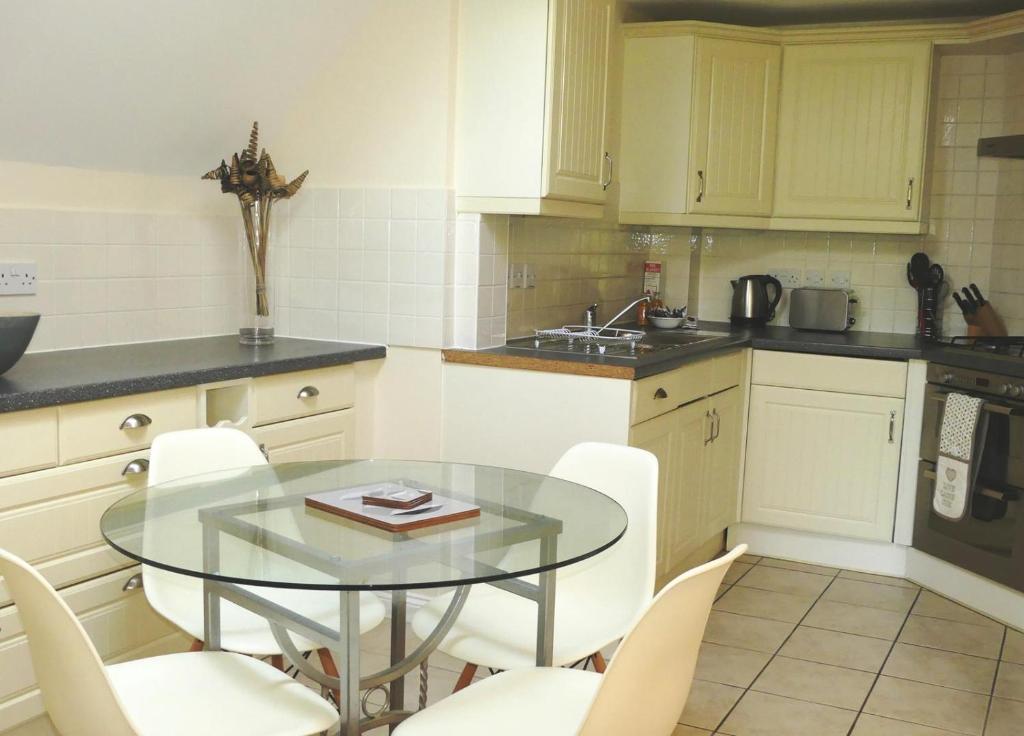 a kitchen with a glass table and white chairs at Basingstoke Apartments - Westlands House, City Centre, Home-From-Home in Basingstoke