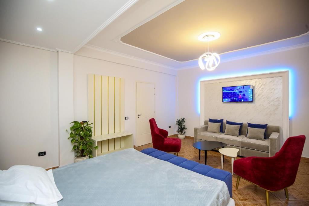 1 dormitorio con cama, sillas rojas y sofá en Hotel Vila Stefa, en Vlorë