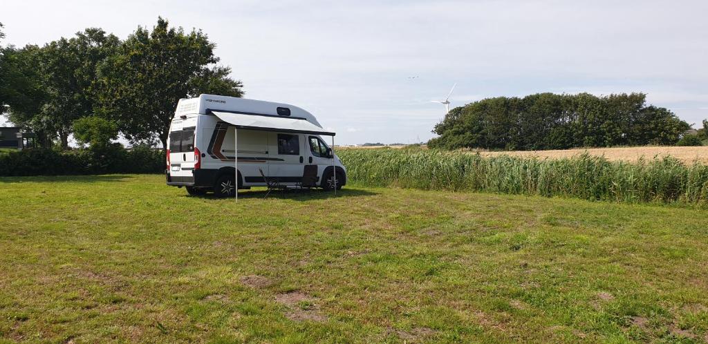 una caravana blanca estacionada en un campo en Wohnmobilstellplatz Hemenswarft an der Nordsee - Meerblick en Emmelsbüll-Horsbüll