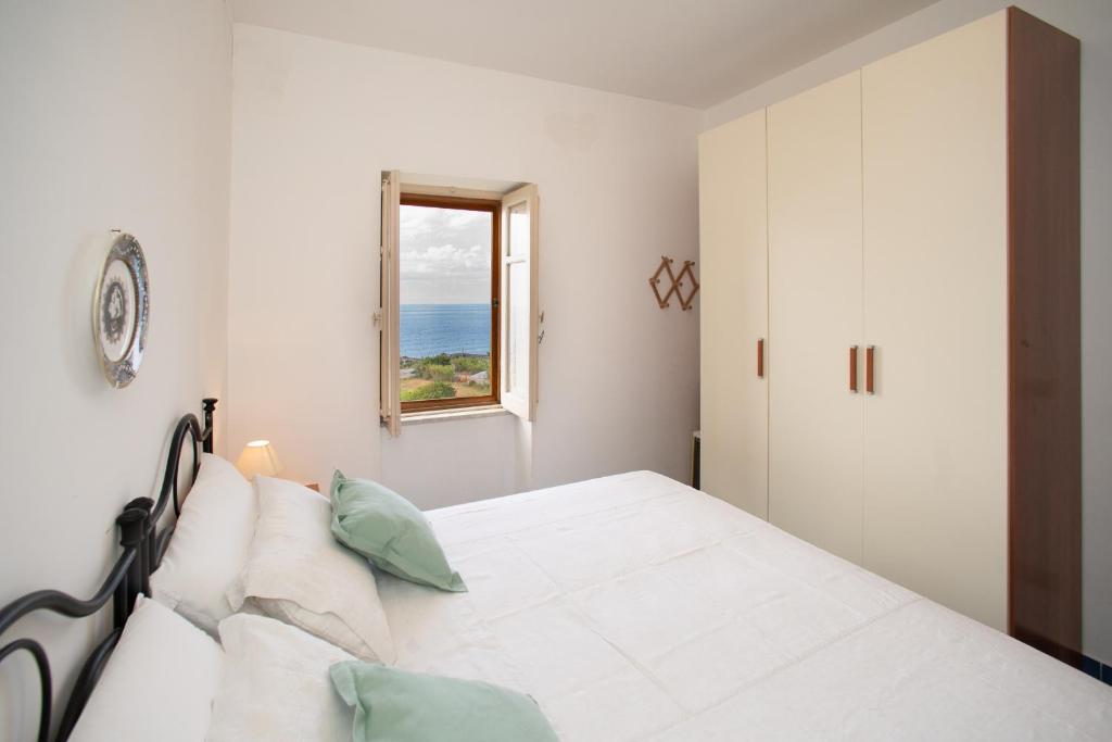 Habitación blanca con cama y ventana en Casa Gallizza con vista mare by Wonderful Italy en Cefalú
