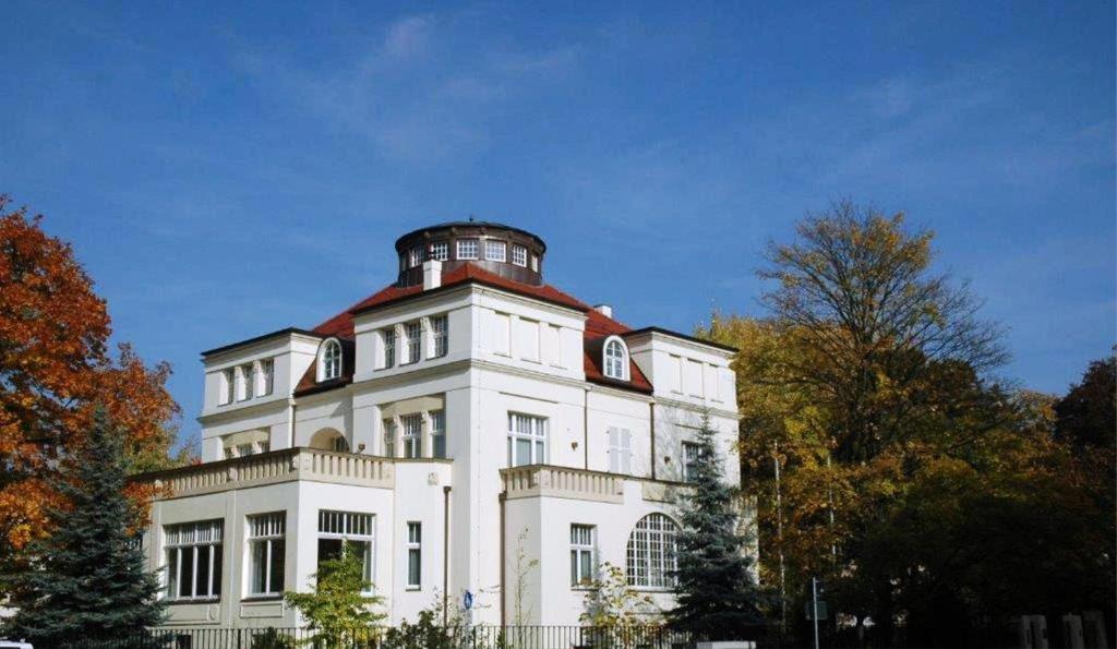 ein großes weißes Gebäude mit einem Turm darüber in der Unterkunft Gästehaus Leipzig in Leipzig