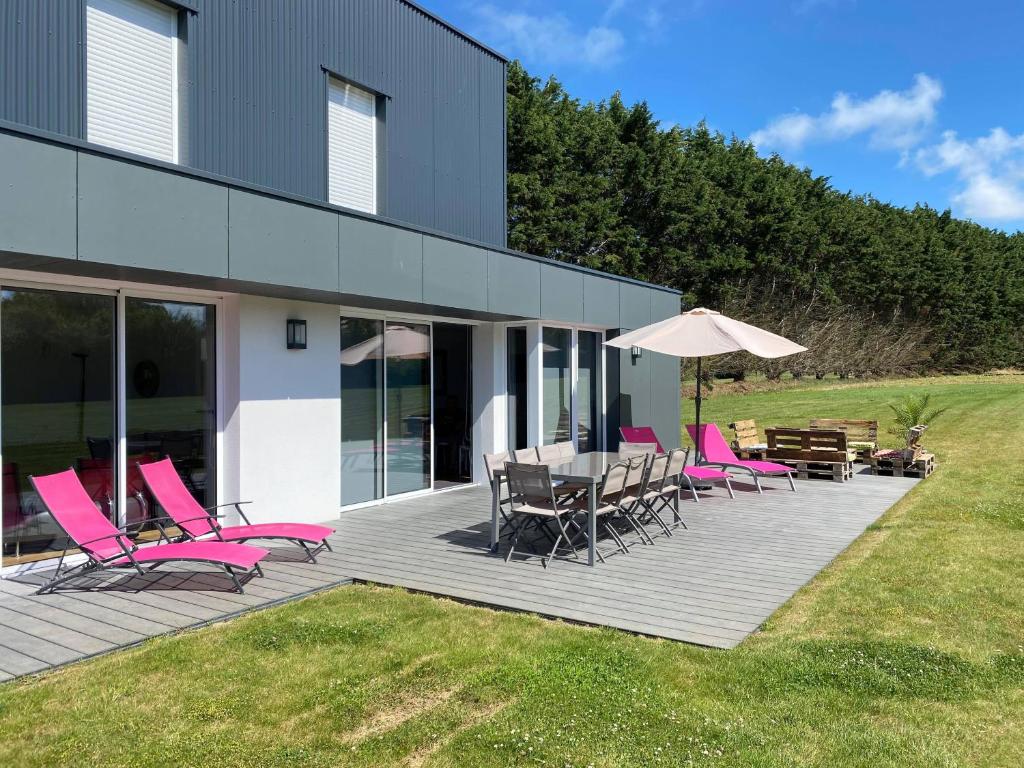 una terraza con sillas, mesas y sombrilla en Villa de l'albatros Sables d'or en Plurien