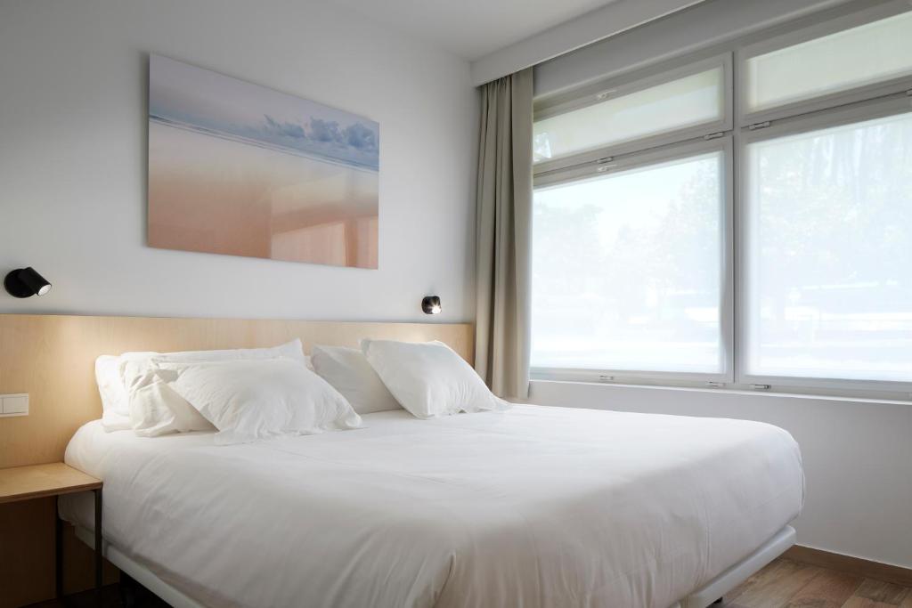 Cama blanca en habitación con ventana grande en Apartamentos Isaga, en Zarautz
