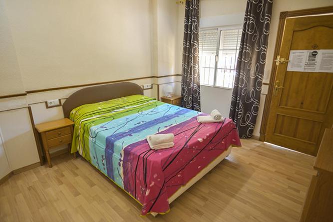 トレビエハにあるLow Cost Marinaのカラフルなベッドとウッドフロアのベッドルーム1室が備わります。