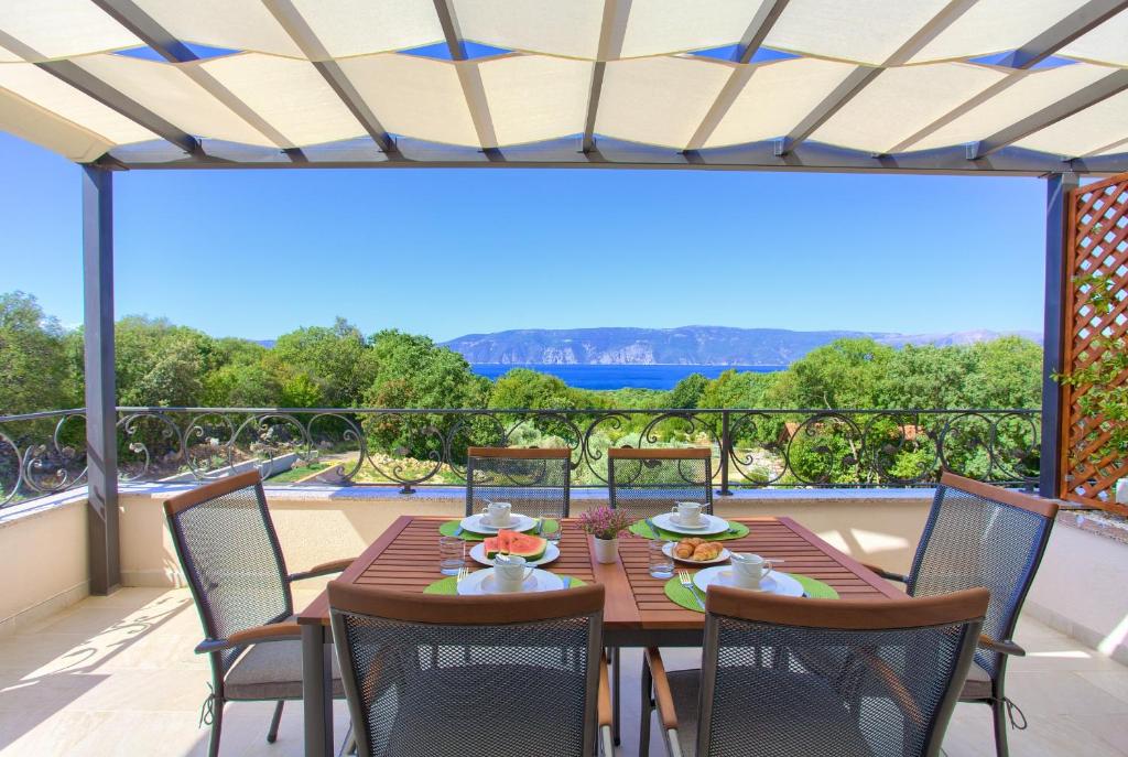 drewniany stół i krzesła na balkonie z widokiem w obiekcie Luxury Apartments Villa Stina w Krku