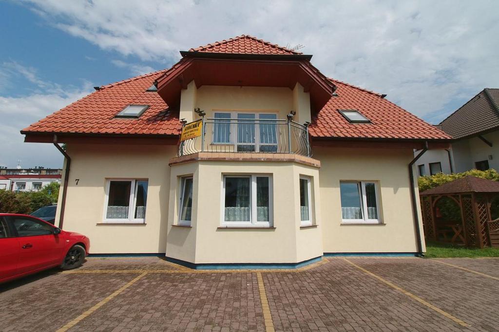 dom z czerwonym dachem na parkingu w obiekcie Siódemka w Dziwnówku w Dziwnówku
