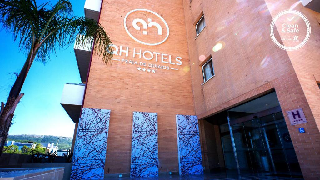 a hotel with a palm tree in front of a building at QH Praia de Quiaios in Praia de Quiaos