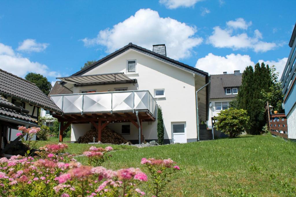 een wit huis met een veranda op een gazon bij Ferienhaus Pape Gleidorf in Schmallenberg