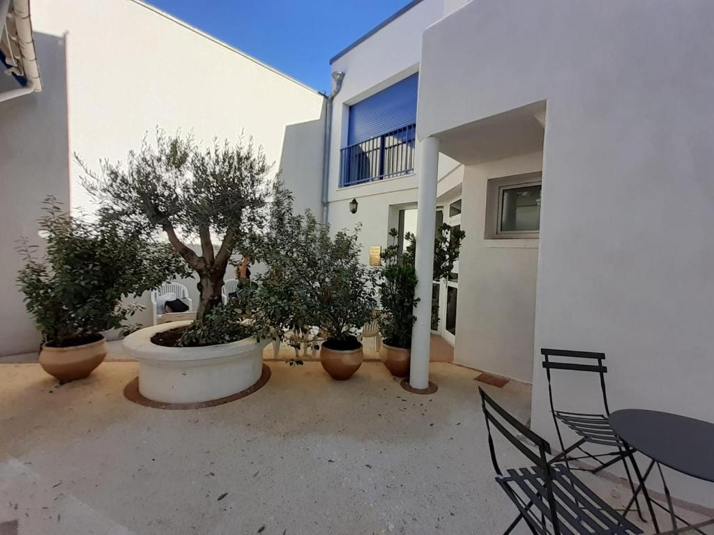 a courtyard with potted plants and a table and chairs at L îlot Grec in Saint-Palais-sur-Mer