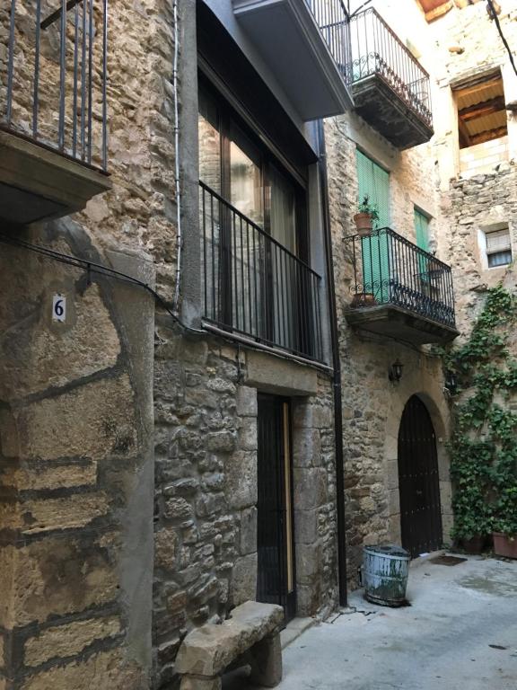 Figuerola de Orcau的住宿－Casa Tato Figuerola d'Orcau，一座石头建筑,设有阳台,前面设有长凳