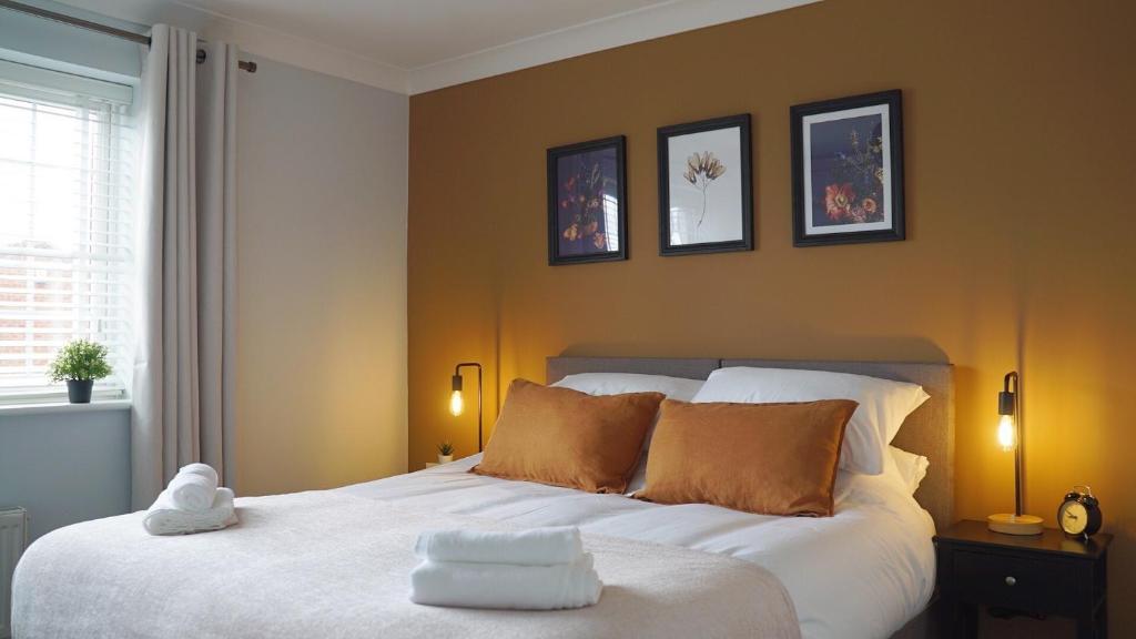 a bedroom with a white bed with three pictures on the wall at The Pavilion - Stunning, 4 Bedroom House with Free Parking in Wakefield