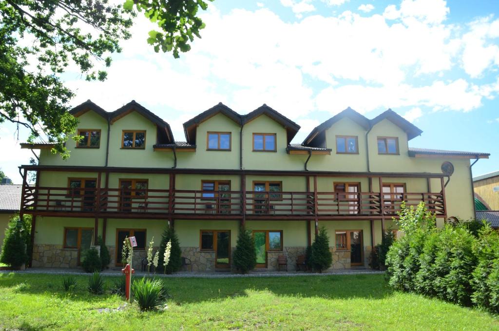 een groot geel huis met een veranda rondom bij Hotel Tenis in Chrząstowice