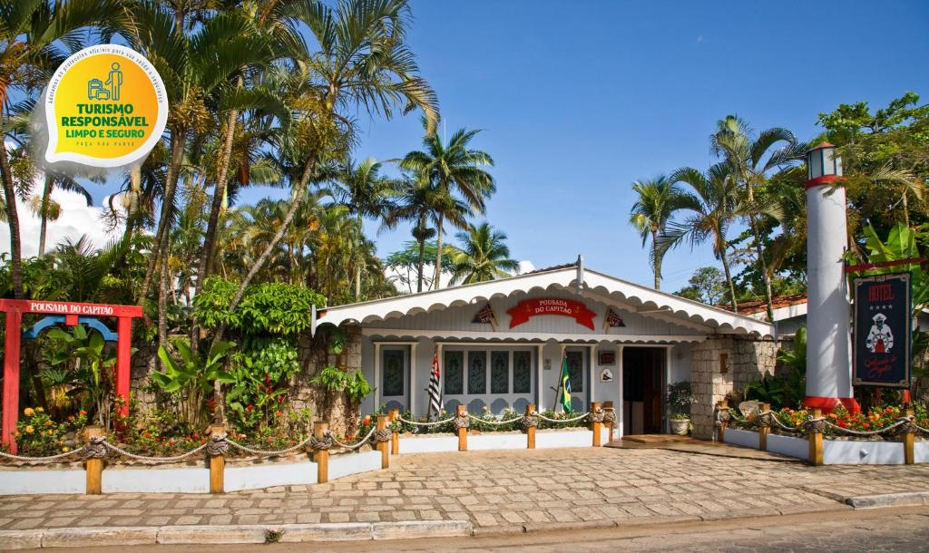 una pequeña casa con palmeras delante en Plaza Inn Pousada do Capitão, en Ilhabela