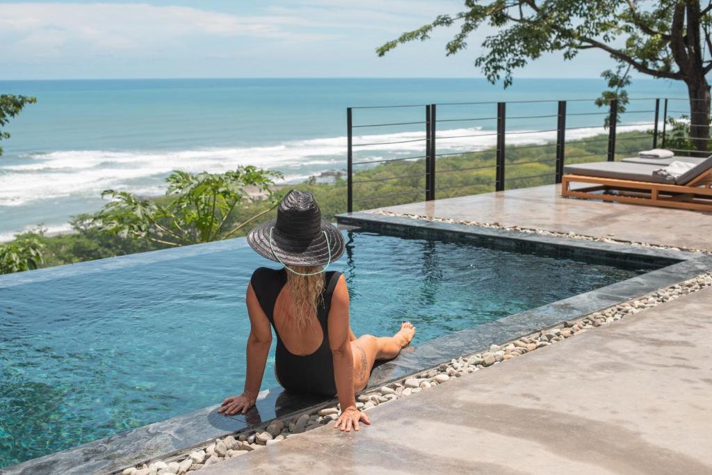 a woman sitting on the edge of a swimming pool at Villa Nof Yam in Santa Teresa Beach