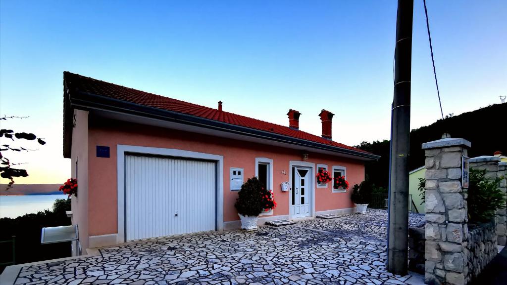 a red building with a garage and a lake at Apartments Solte in Mošćenice