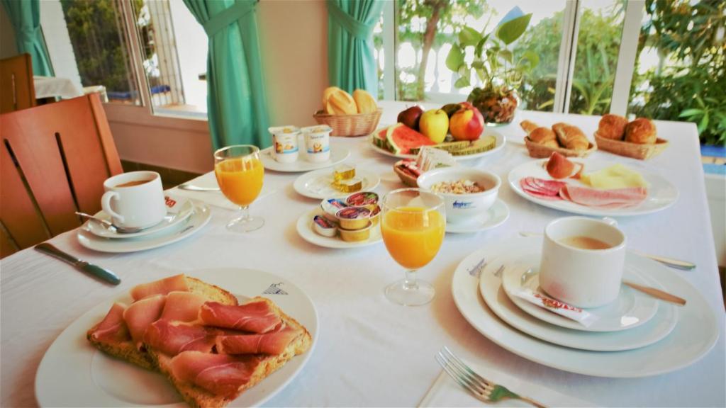 a table with plates of food and cups of orange juice at Hotel Ayamontino in Punta Umbría
