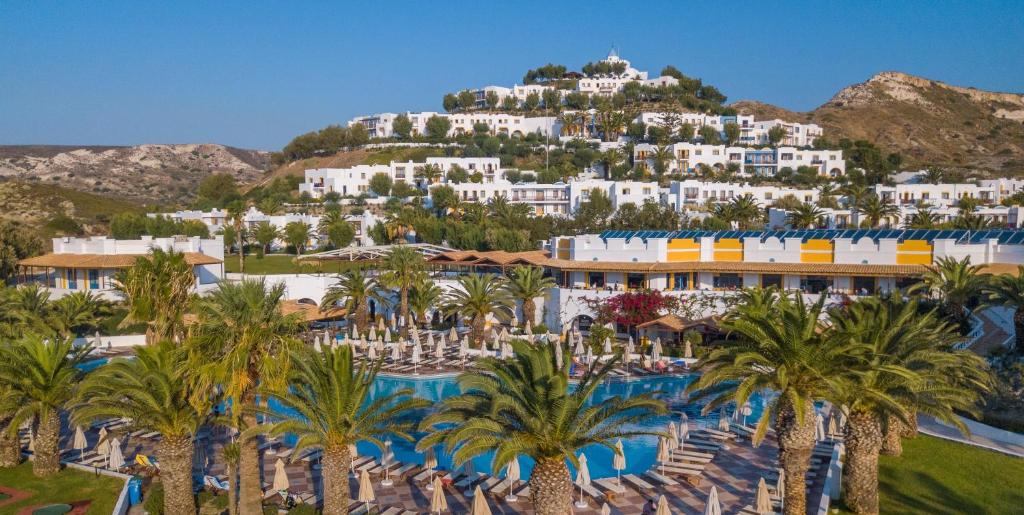 a resort with palm trees in front of a mountain at Lagas Aegean Village in Kardamaina